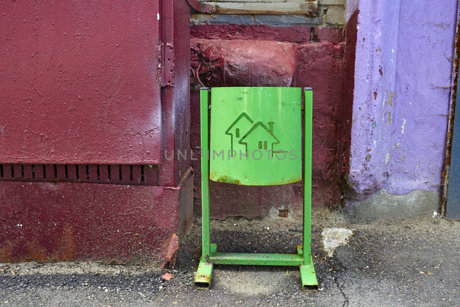 a green trash can on tof a house wall. by electrovenik