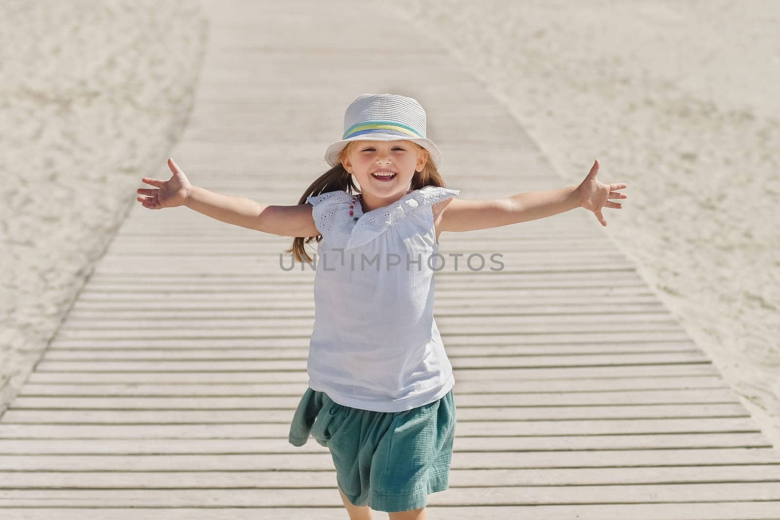 Little girl in a hat running on the beach