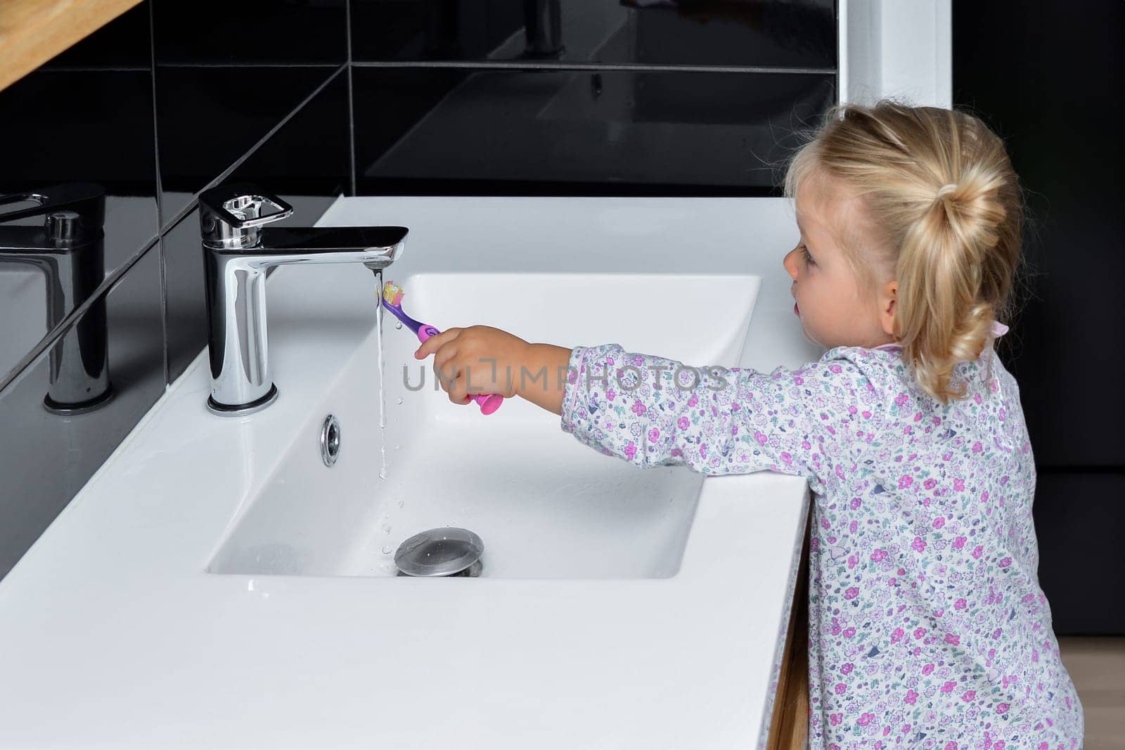 Little girl brushing teeth in the bath by Godi