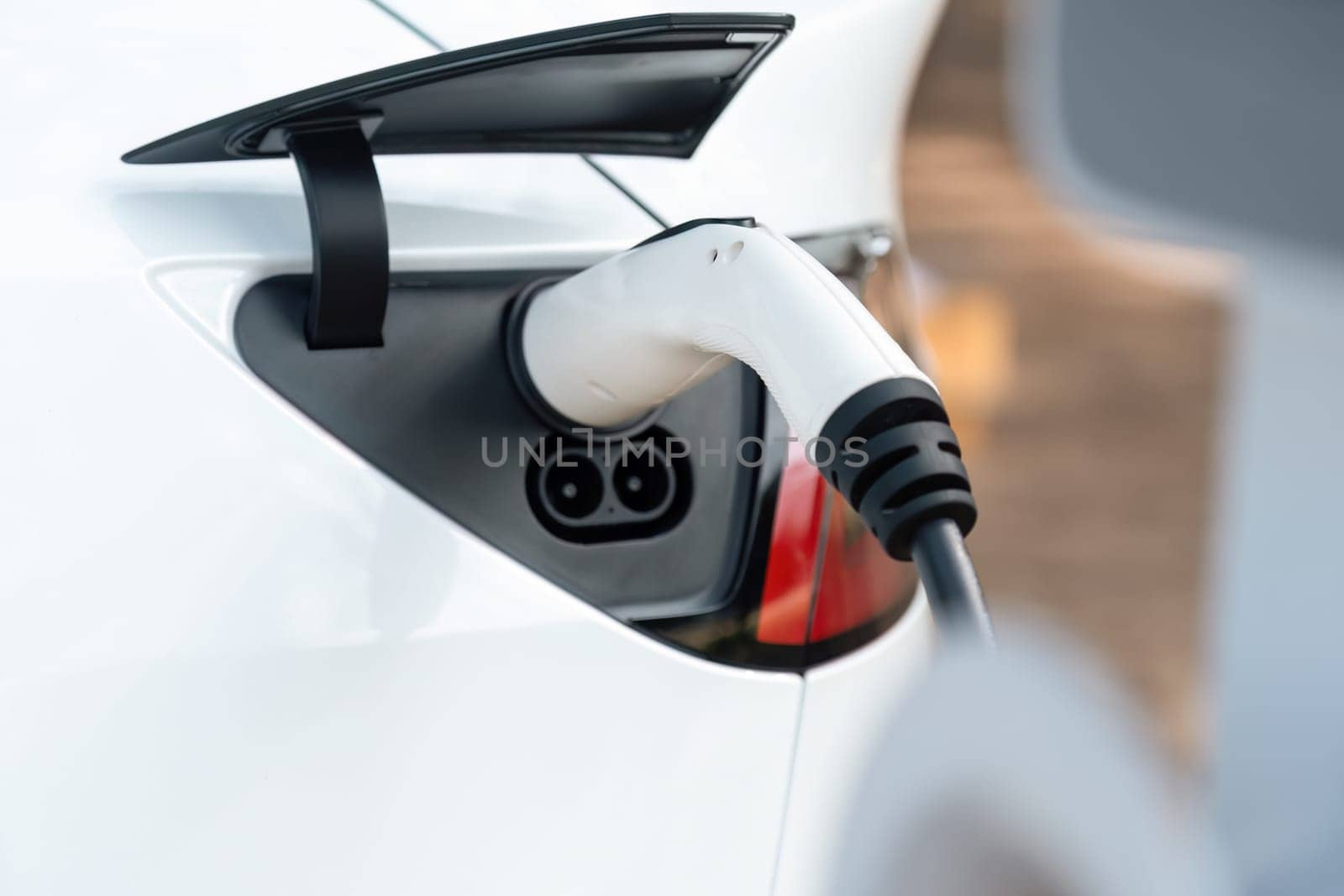 Closeup EV charger handle plugged in or connect to electric car, recharging EV car battery with alternative and sustainable energy with zero CO2 emission for clean environment. Perpetual