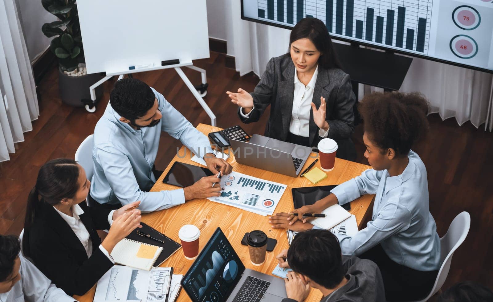 Multiracial analyst team use BI Fintech software to analyze financial data on meeting. Top view finance dashboard data display on laptop screen with analyzed chart for marketing indication. Concord