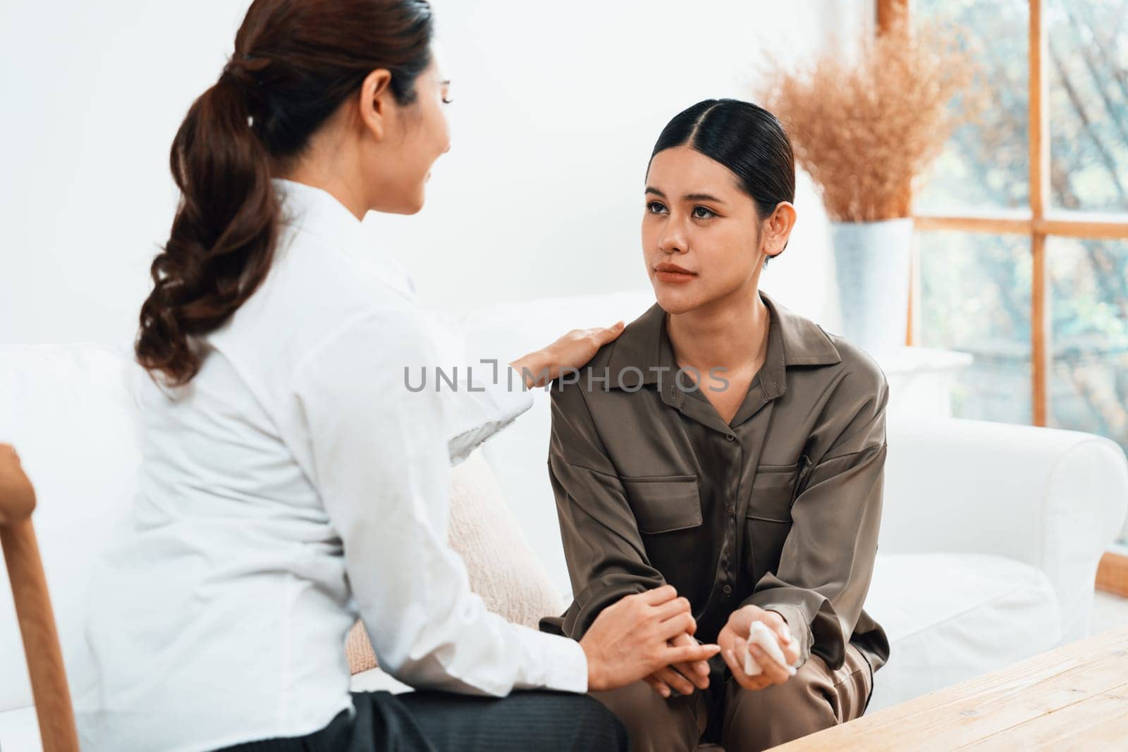 Sad PTSD woman patient in uttermost therapy for mental health with psychologist, depression or grief after life failure. Frustrated trauma young woman talking to a psychologist about emotion in clinic