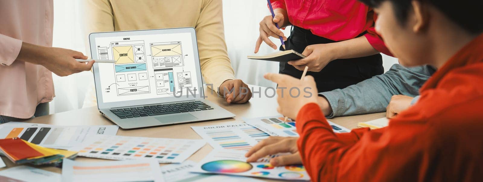 Cropped image of interior designer team discuss the material color while laptop displayed website wireframe designs for mobiles app and website. Creative design and business concept. Variegated.