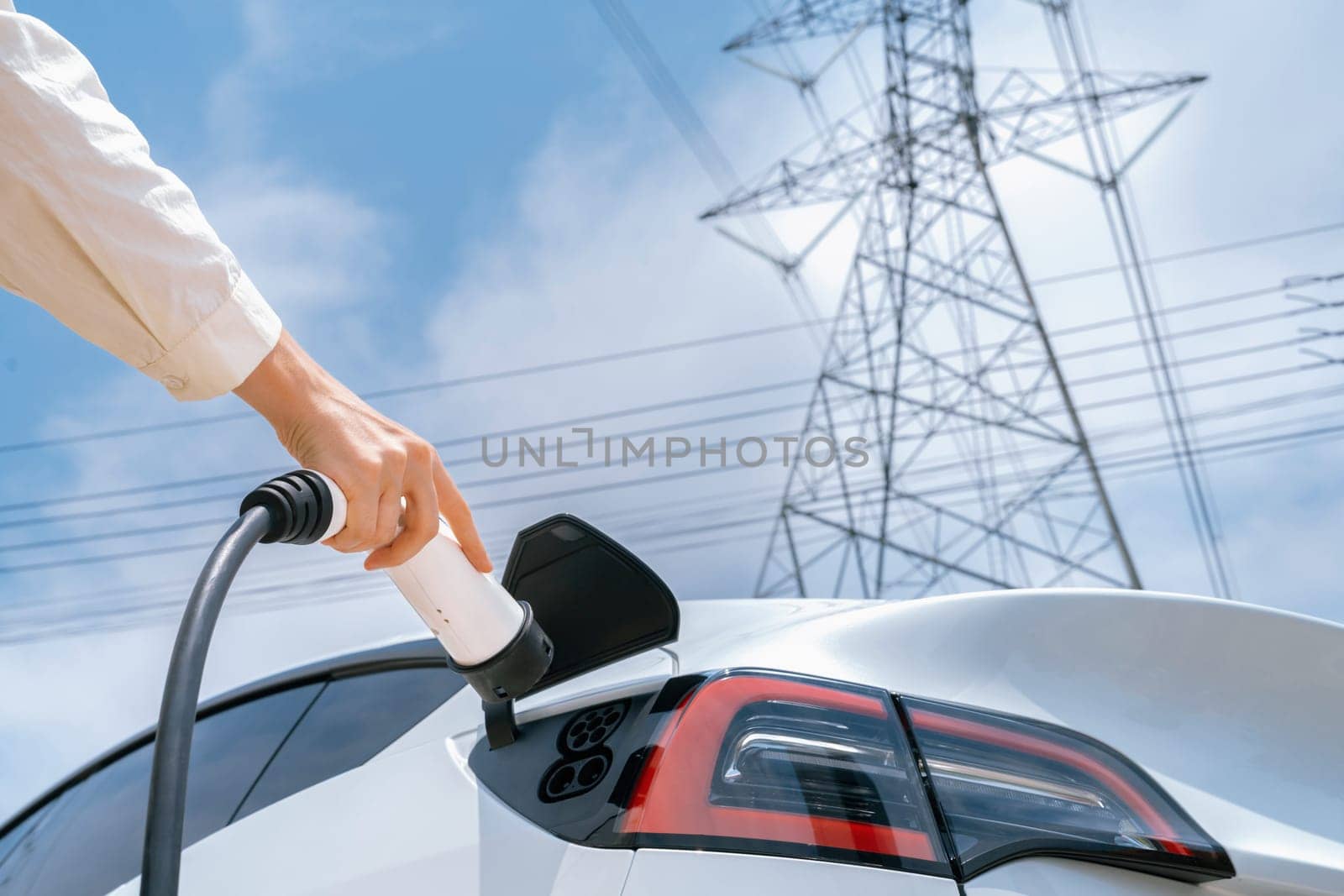 Closeup woman recharge EV electric car battery at charging station. Expedient by biancoblue