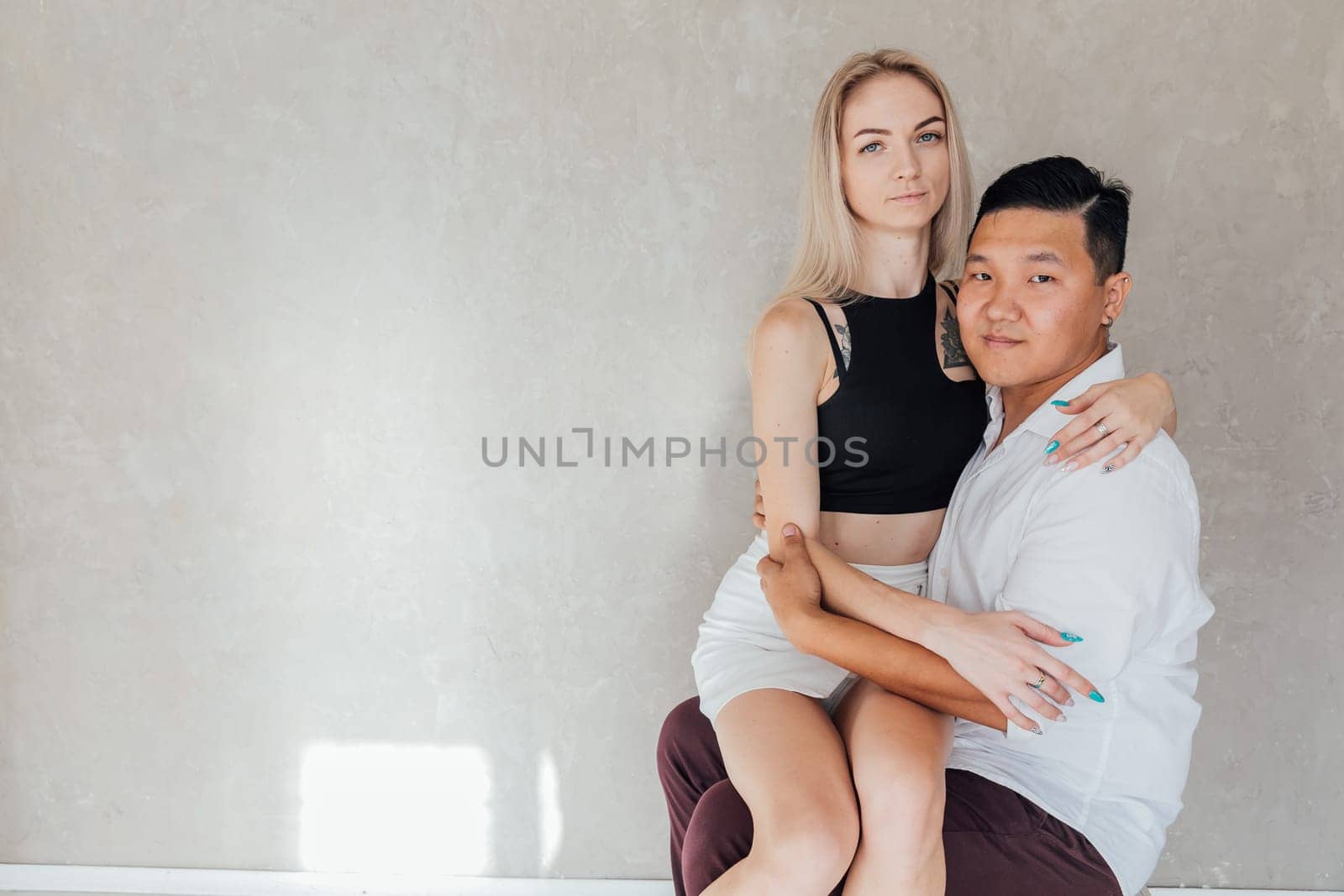 a woman sits on a man on a gray background by Simakov