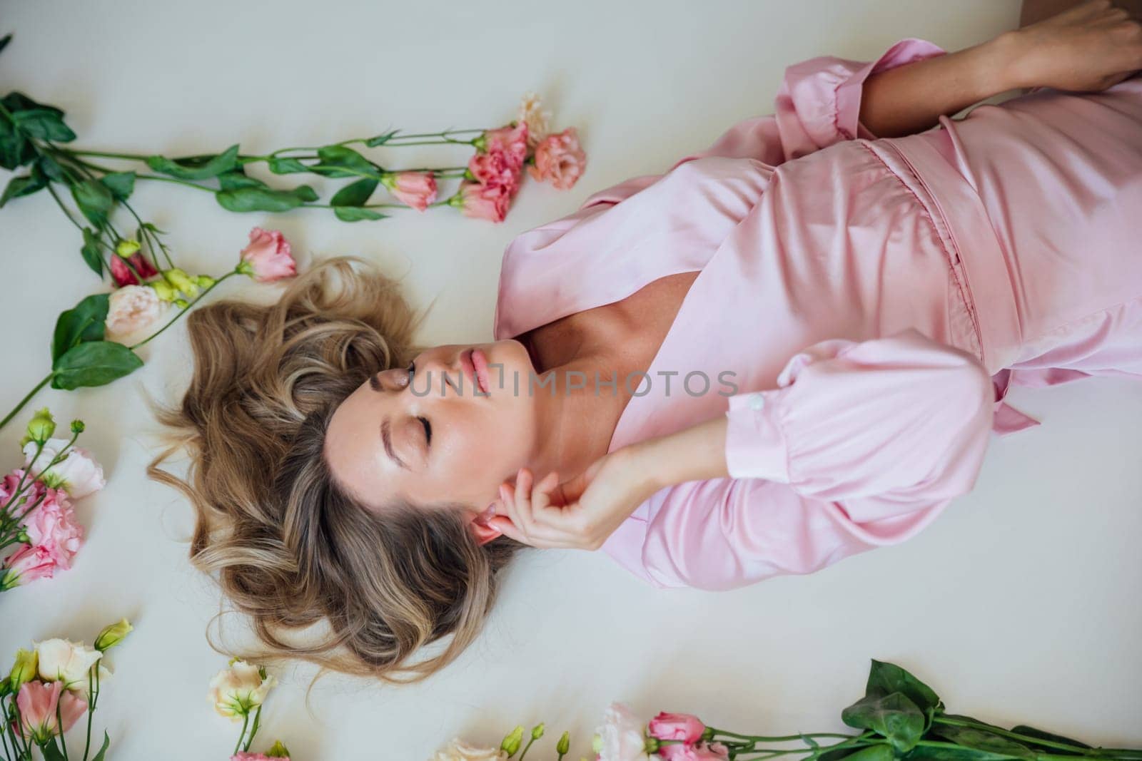 a beautiful blonde lies in flowers in the room