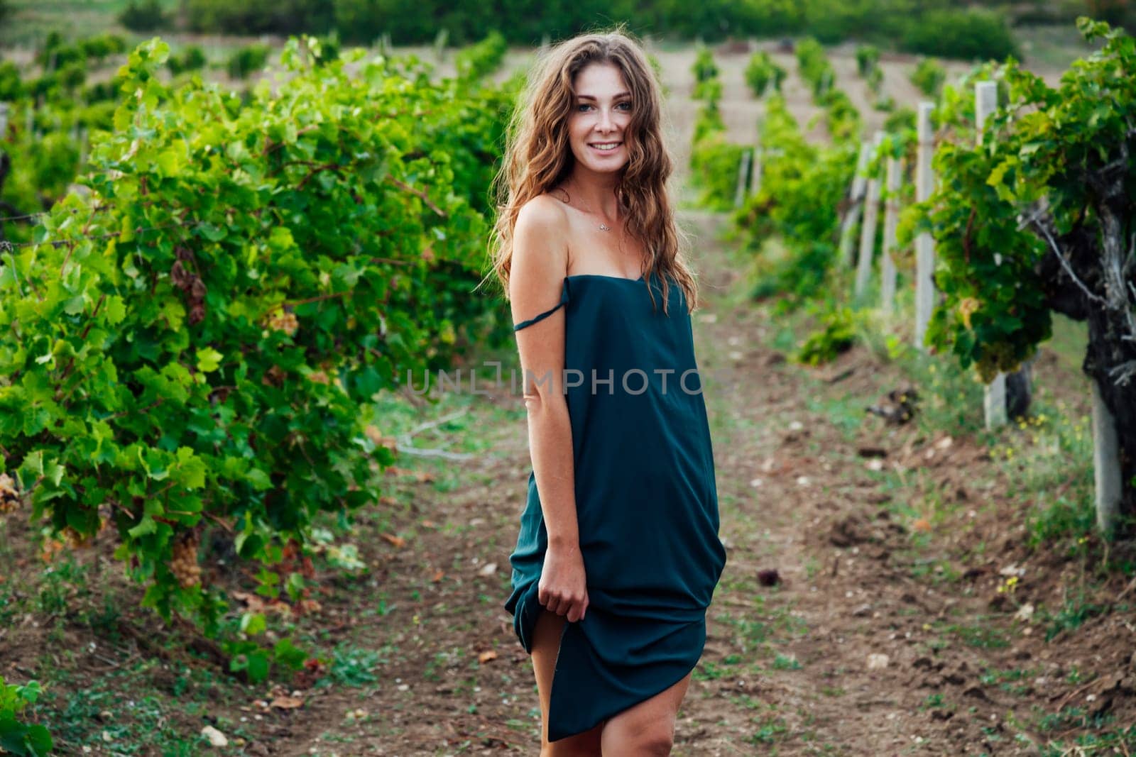 a woman in green dress in vineyard walk