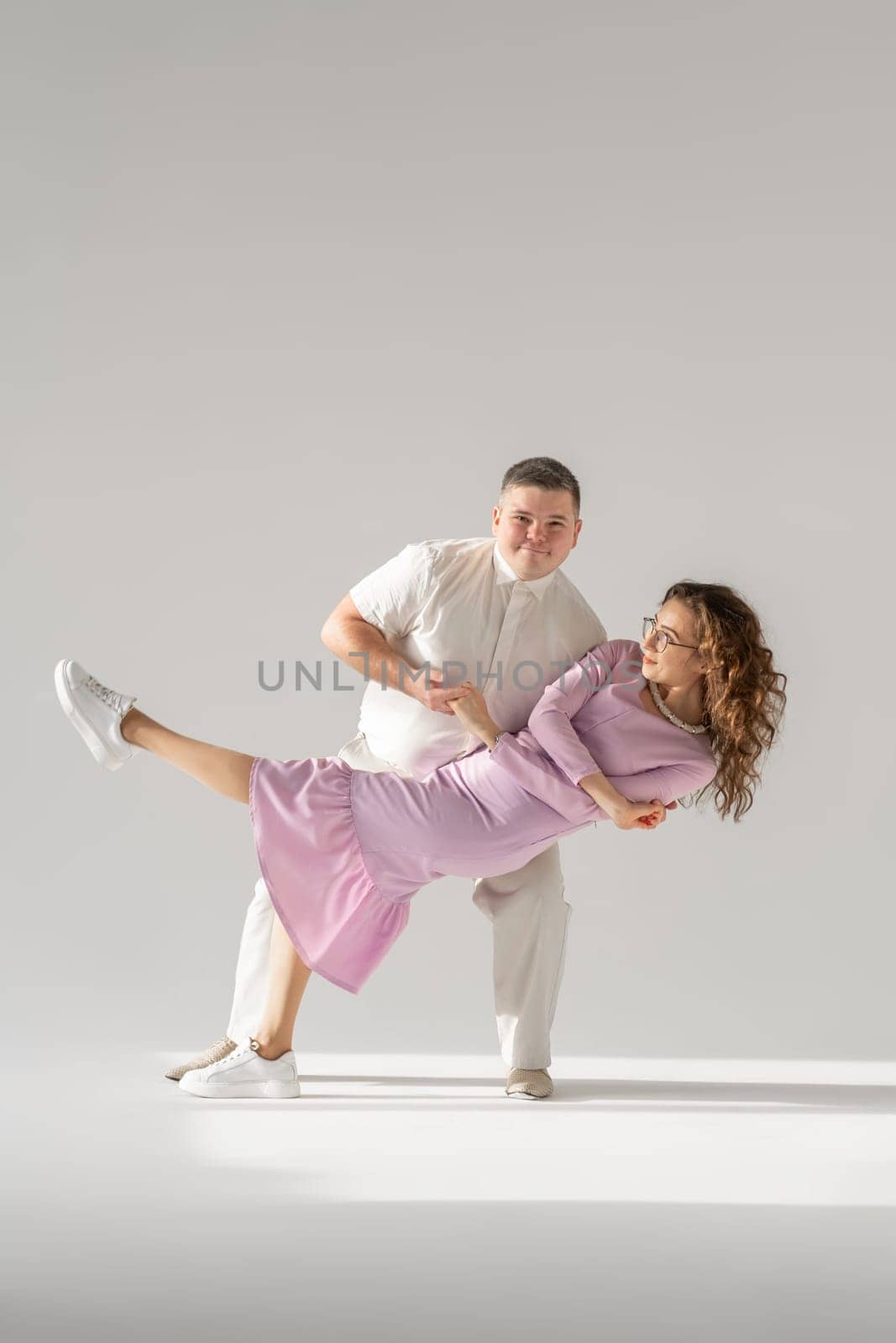 Beautiful young couple dancing on light background. by AnatoliiFoto