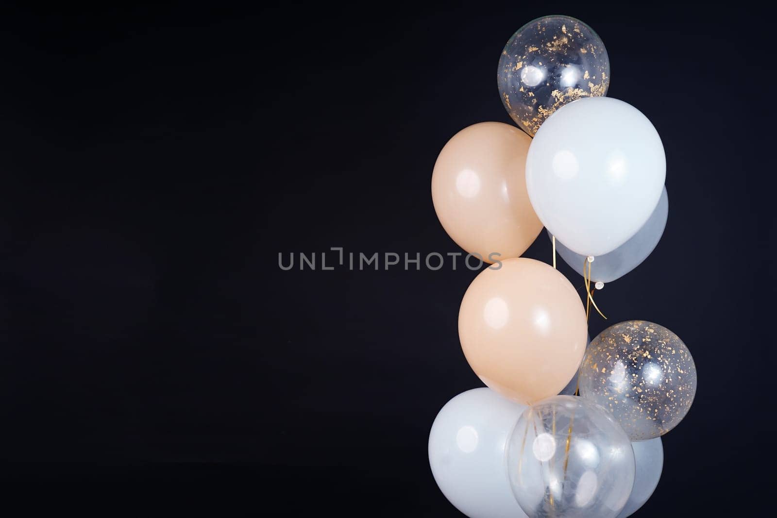 On a black background, balloons of light shades - white, beige, transparent - are flying. Space for text by tewolf