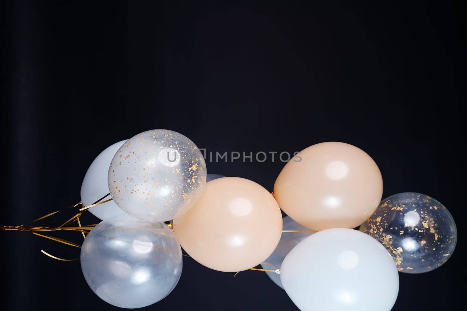 A bunch of balloons in white, beige and transparent colors on a dark background with space for an inscription. High quality photo