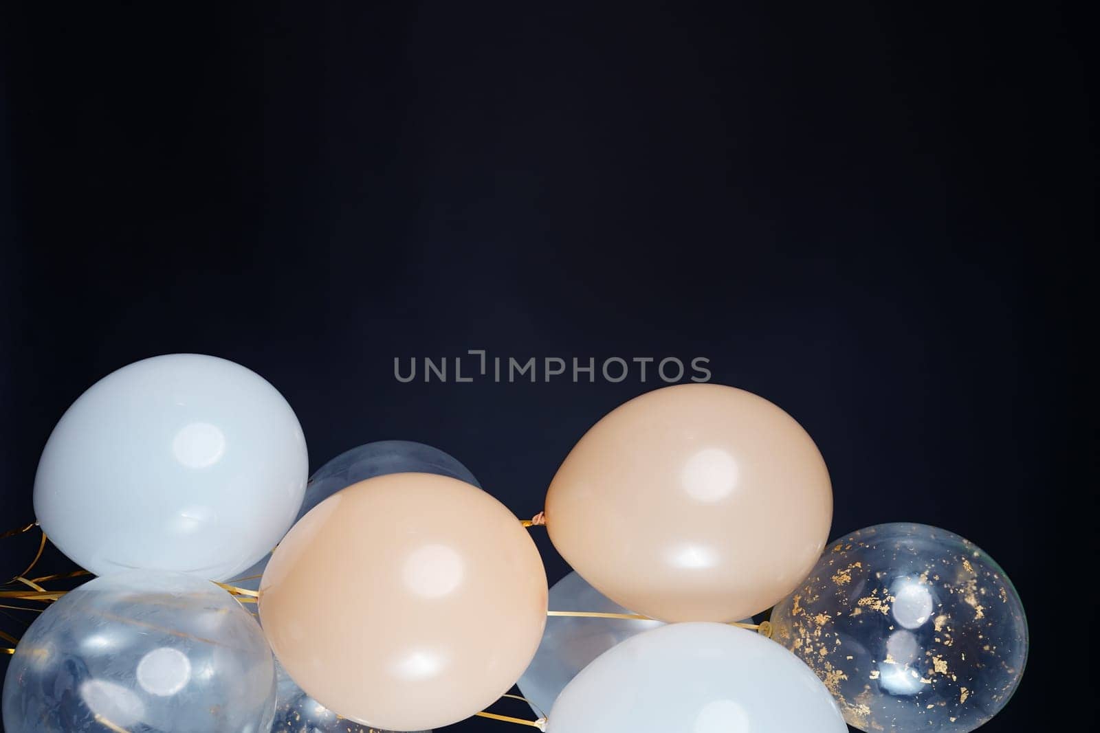 On a black background, balloons of light shades - white, beige, transparent - are flying. Space for text by tewolf