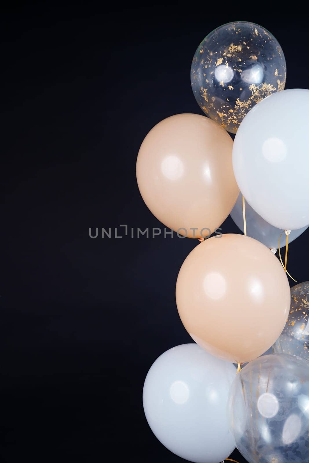 On a black background, balloons of light shades - white, beige, transparent - are flying. Space for text by tewolf