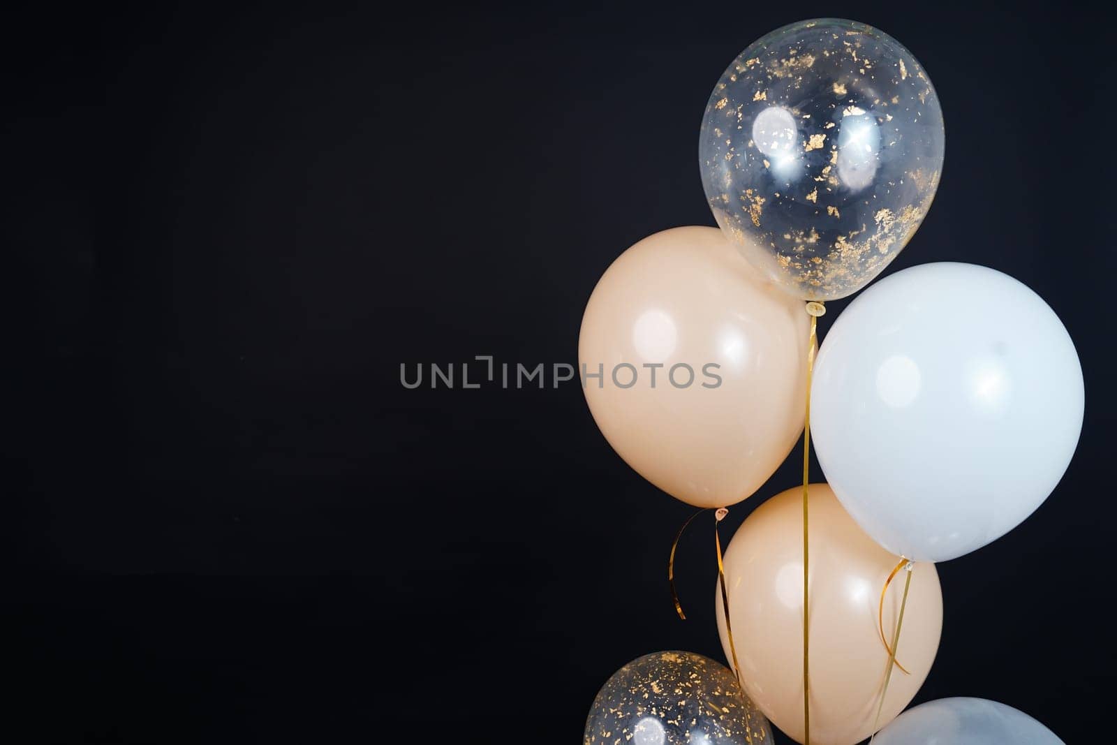 Bunch of balloons of white, beige and transparent colors on a dark background. Place for the inscription. High quality photo