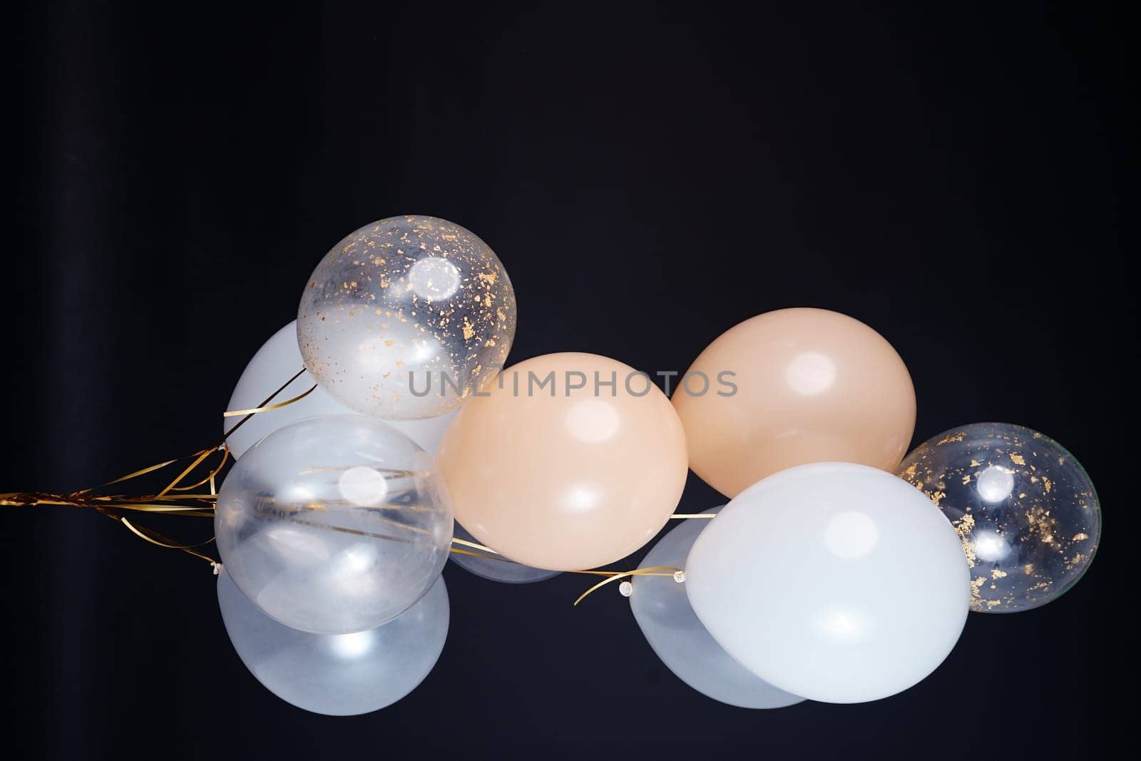 A bunch of balloons in white, beige and transparent colors on a dark background with space for an inscription. High quality photo