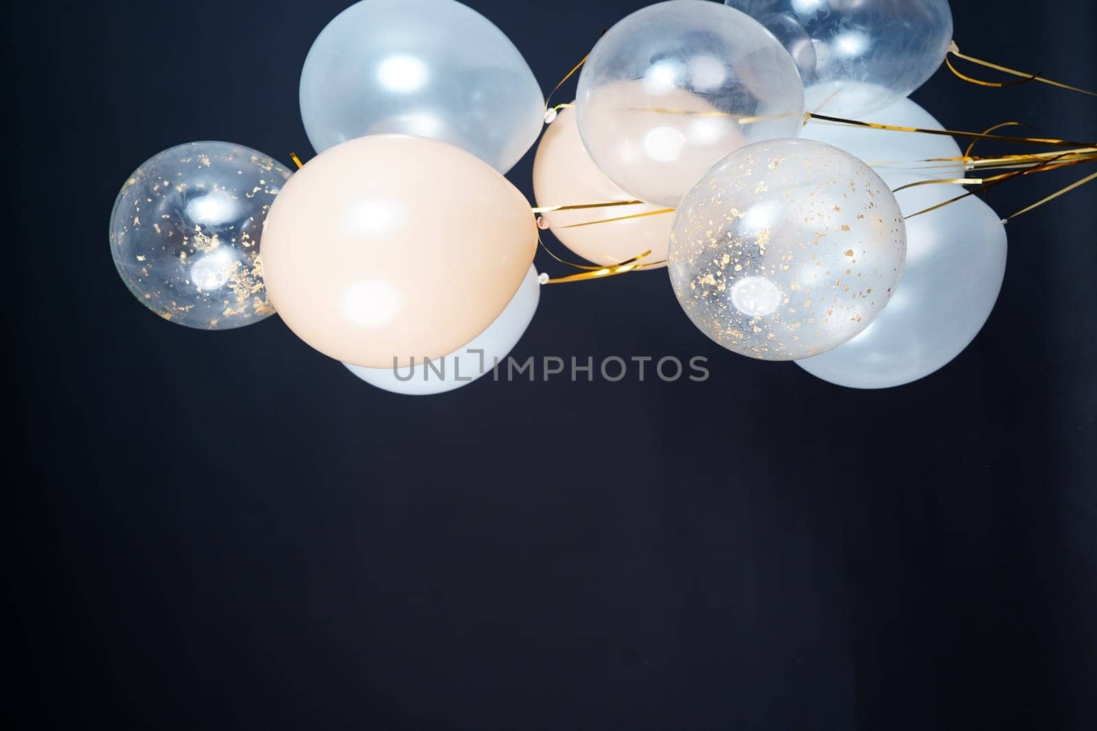 On a black background, balloons of light shades - white, beige, transparent - are flying. Space for text by tewolf