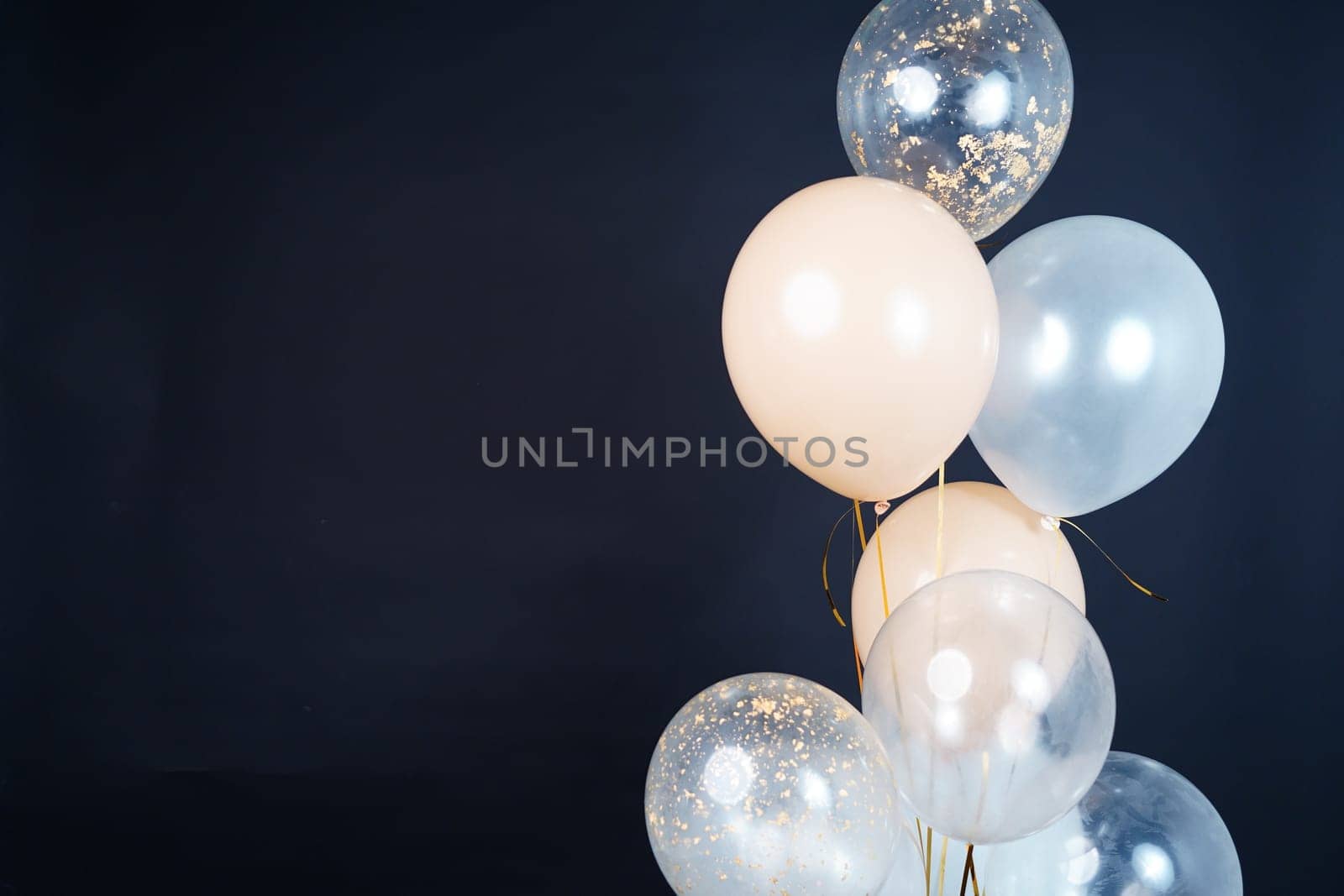 Bunch of balloons of white, beige and transparent colors on a dark background. Place for the inscription. High quality photo