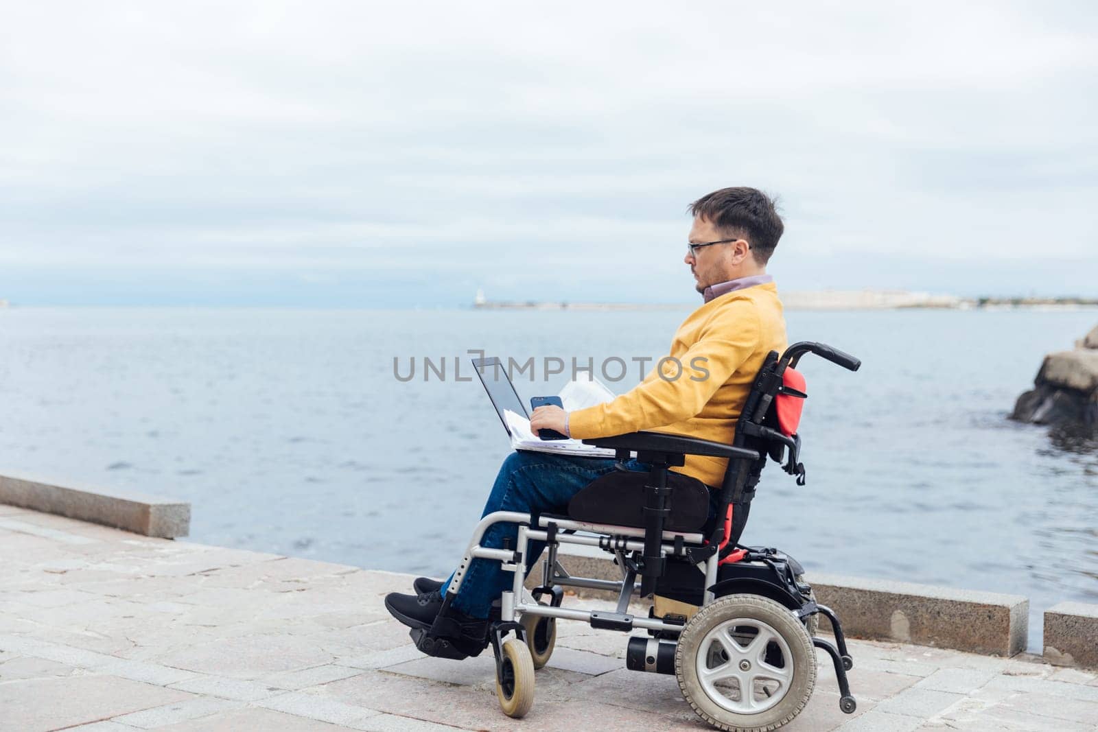 person with disabilities near the sea works at a laptop