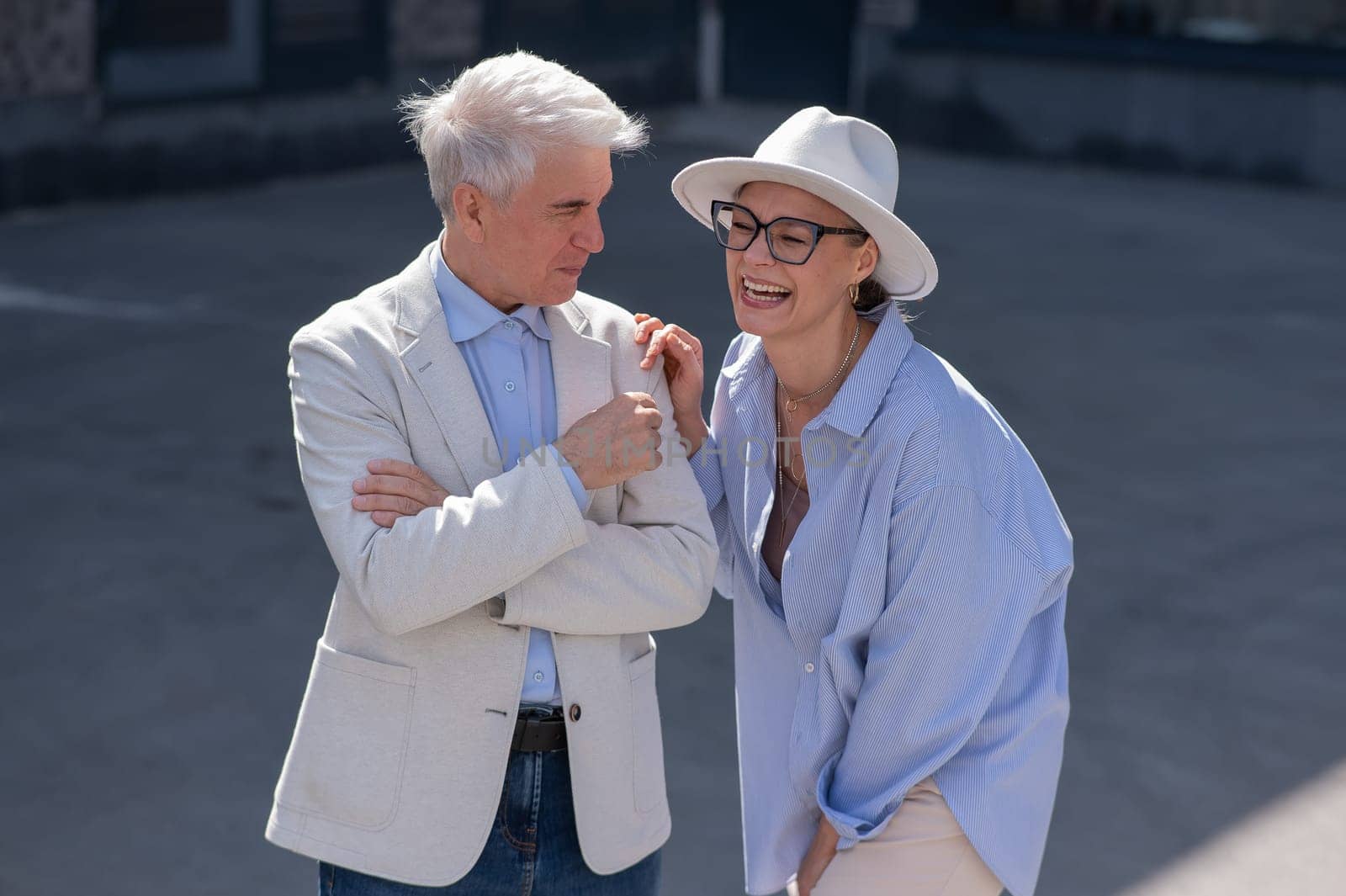 Stylish elderly laughing couple on a walk. Romantic relationships of mature people