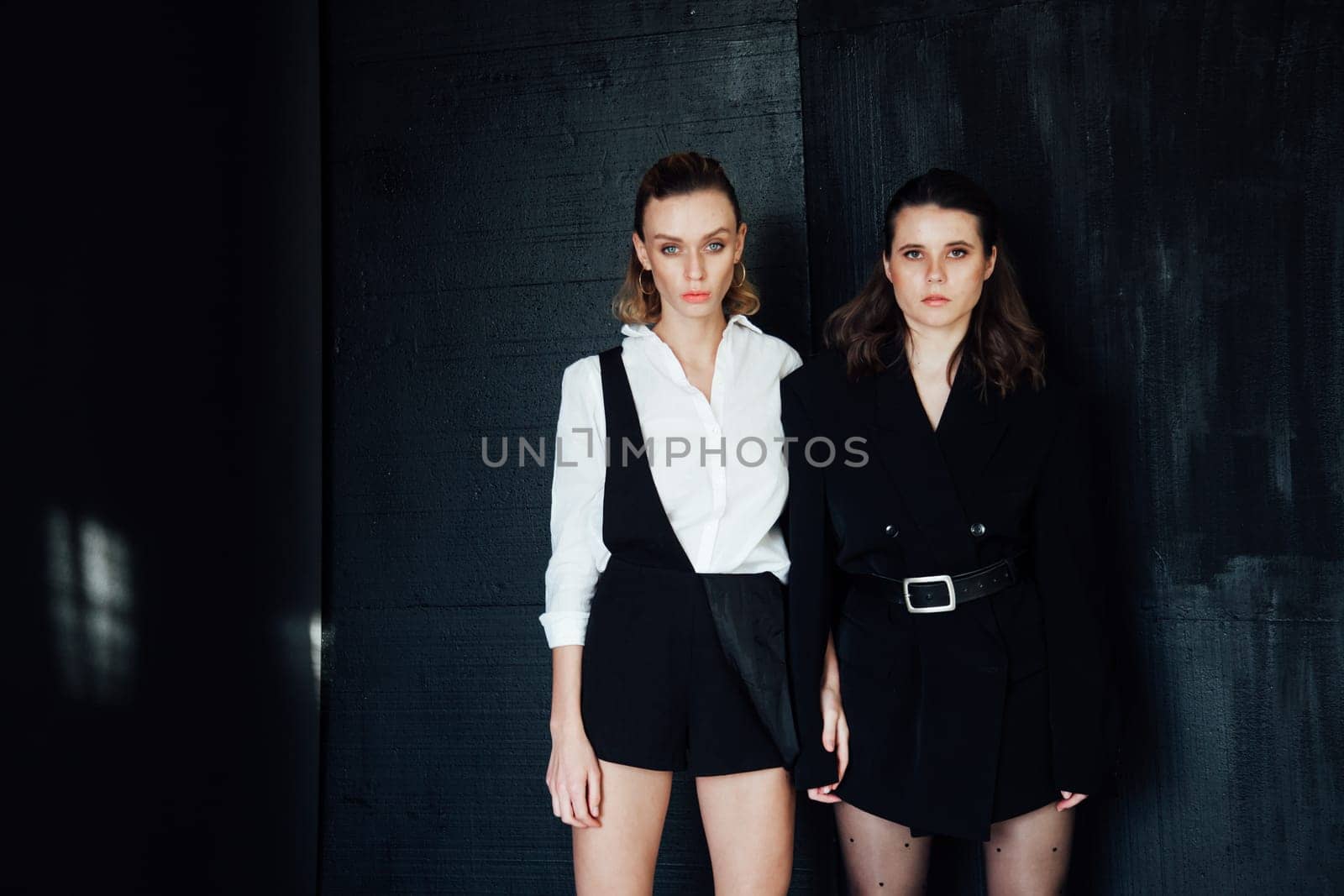 two women pose on a black background by Simakov