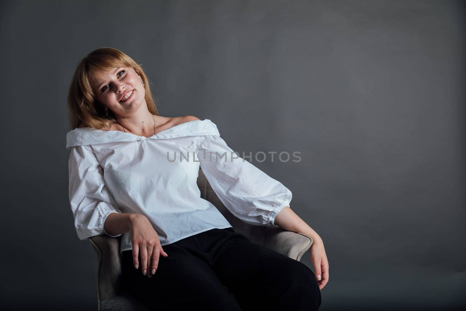 beautiful woman sitting in a chair on a gray background