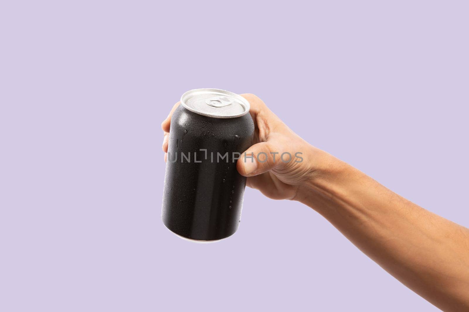 Close-up of hand holding Empty aluminum can with condensation isolated on purple by TropicalNinjaStudio