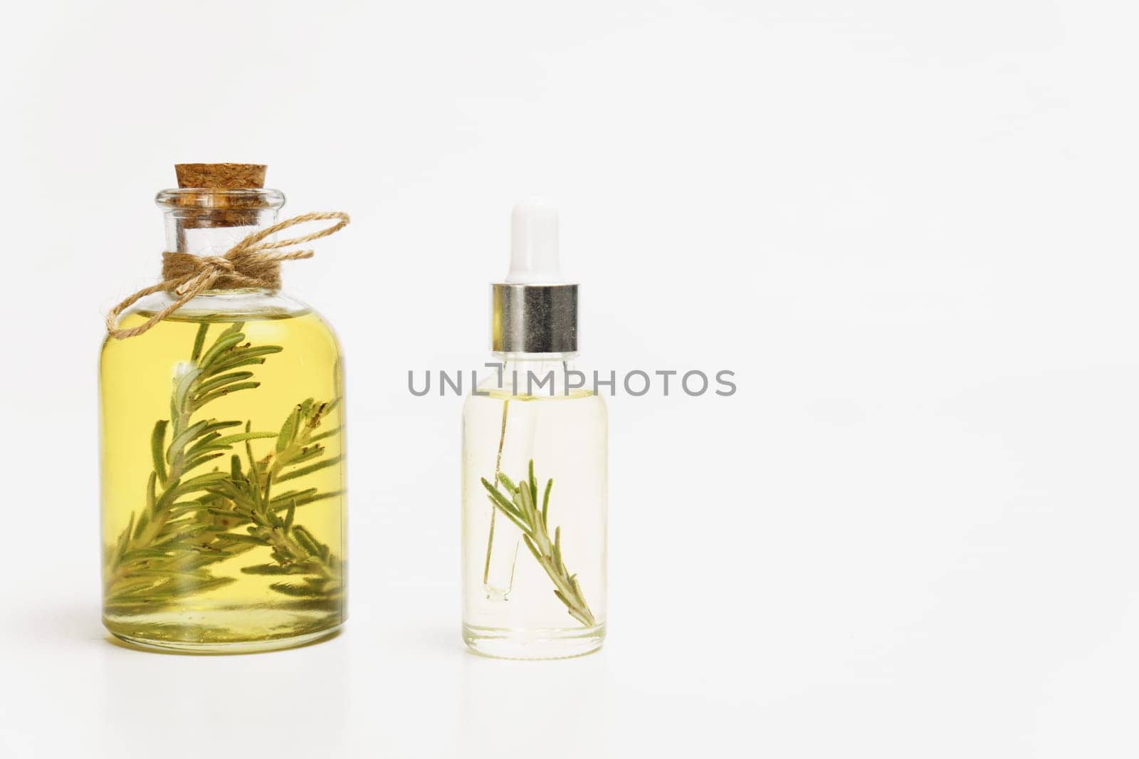 bottle and dropper with rosemary essential oil with fresh branches inside isolated on white background and copy space