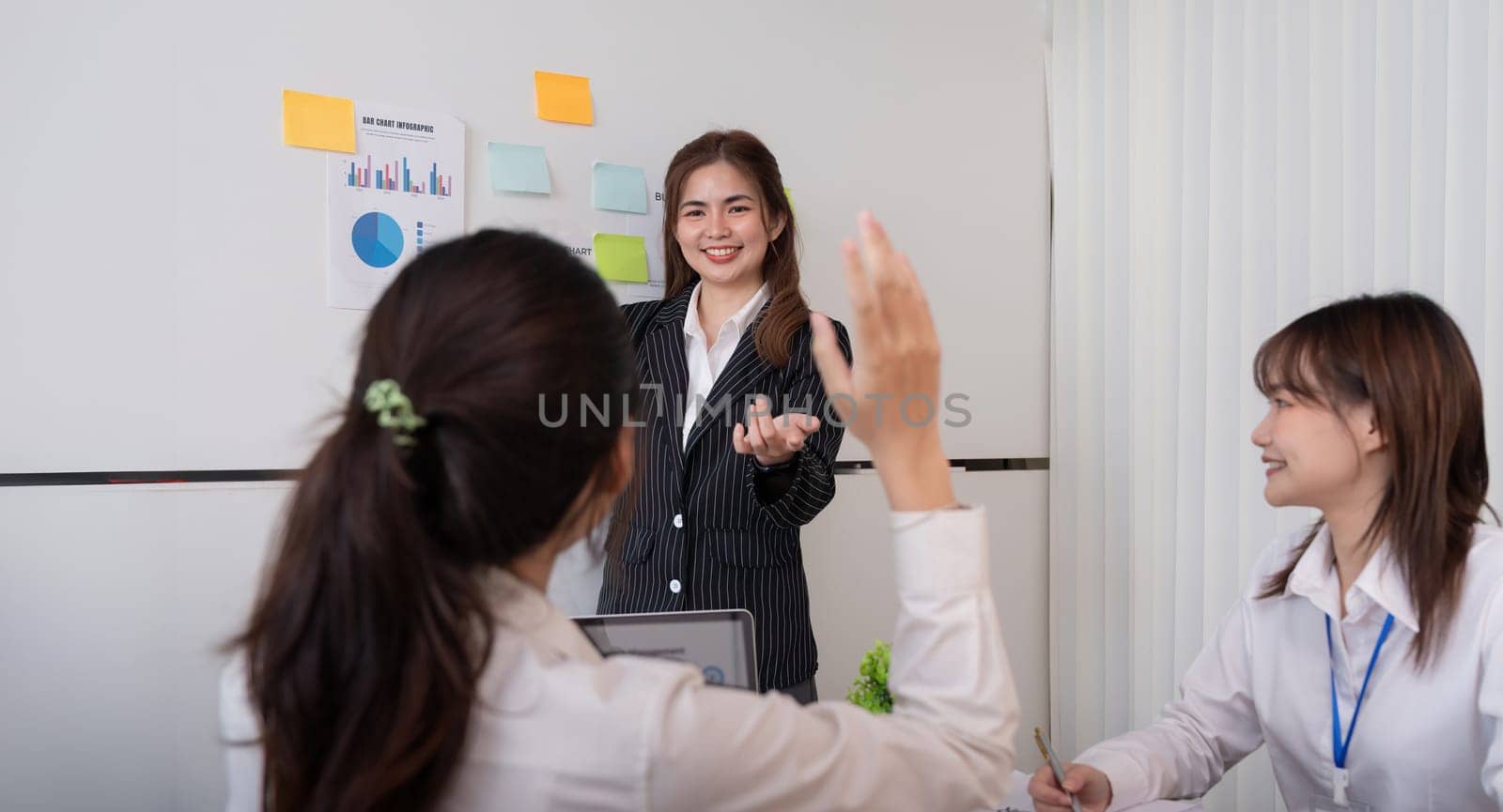 Business woman presentation and female employee ask question during work training, motivated confident female employee raise hand answer engaged in teamwork at seminar.