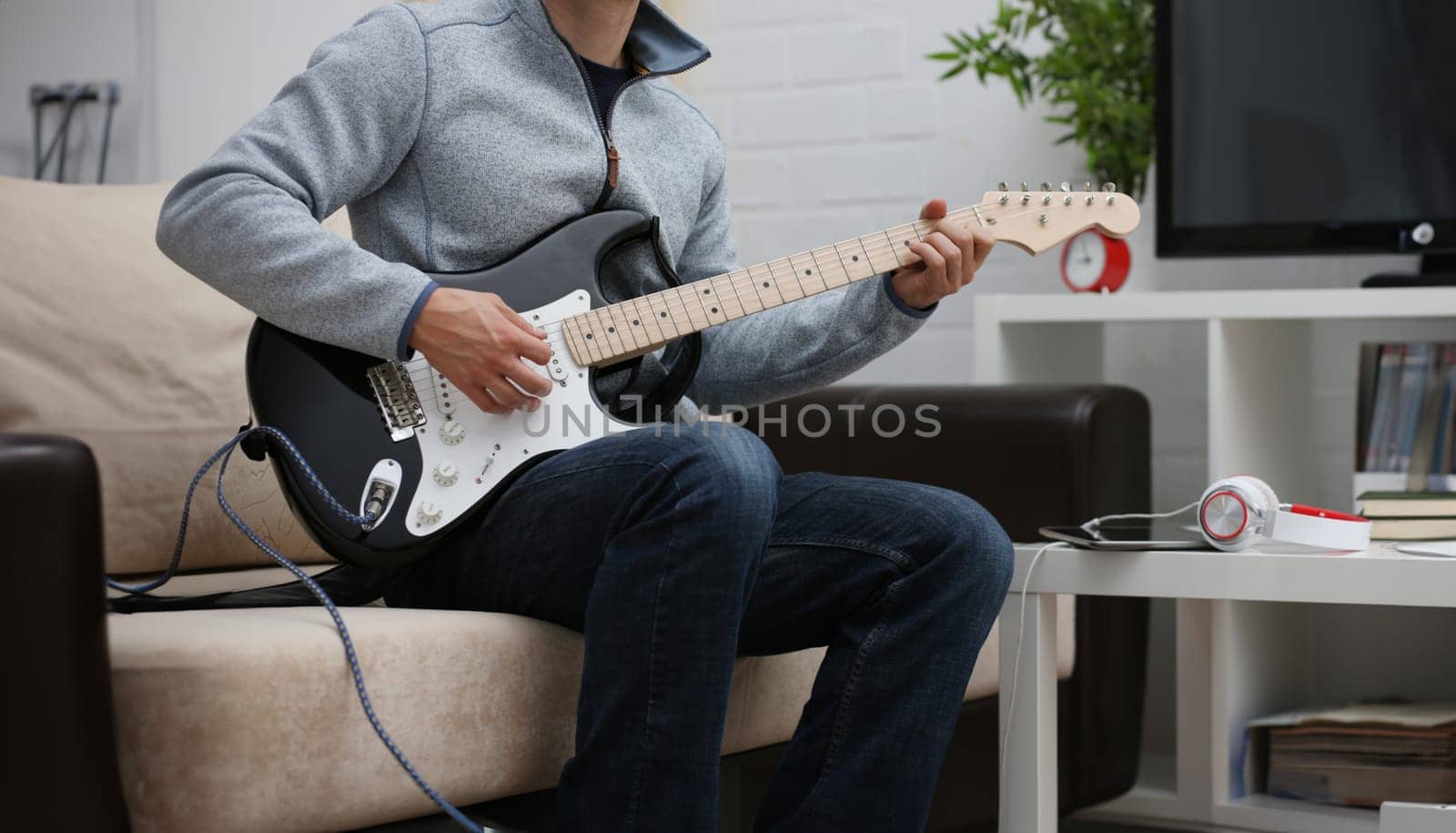 Male hands at home play and tune the electric guitar is engaged in music realizes listening enjoying music notation large concept closeup