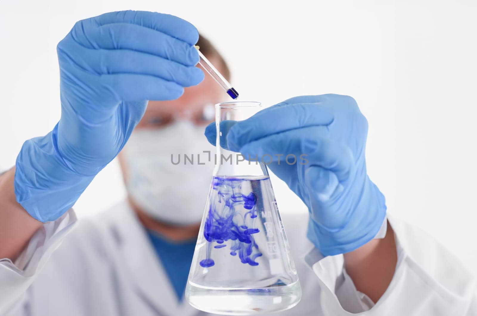 A male chemist holds test tube of glass in his hand overflows a liquid solution of potassium permanganate conducts an analysis of water samples versions of reagents using chemical manufacturing.