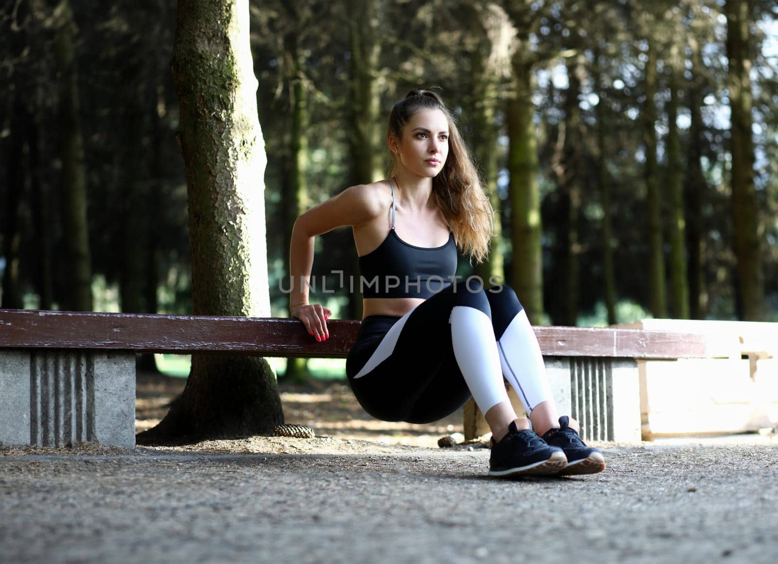 Portrait of wonderful woman pumping buttocks muscles. Beautiful sportswoman in fashionable sportswear looking away with concentration. Fitness and sport concept