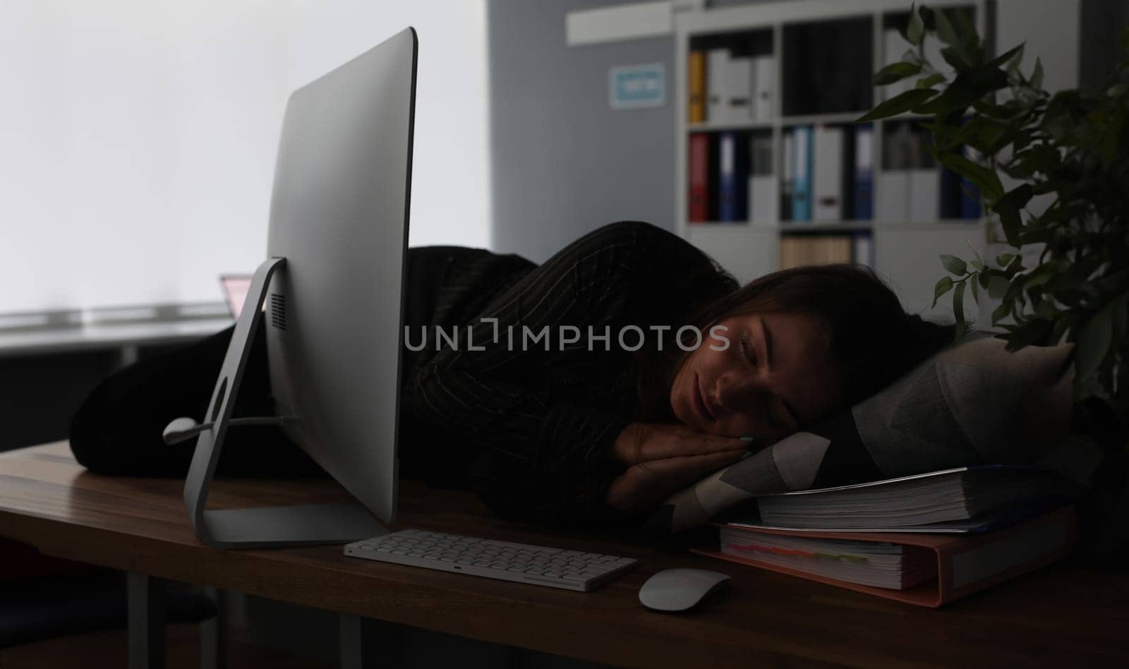 Businesswoman sleeping on office table evening time background. Woman wants to go home and lives at work. Overtime night work concept.