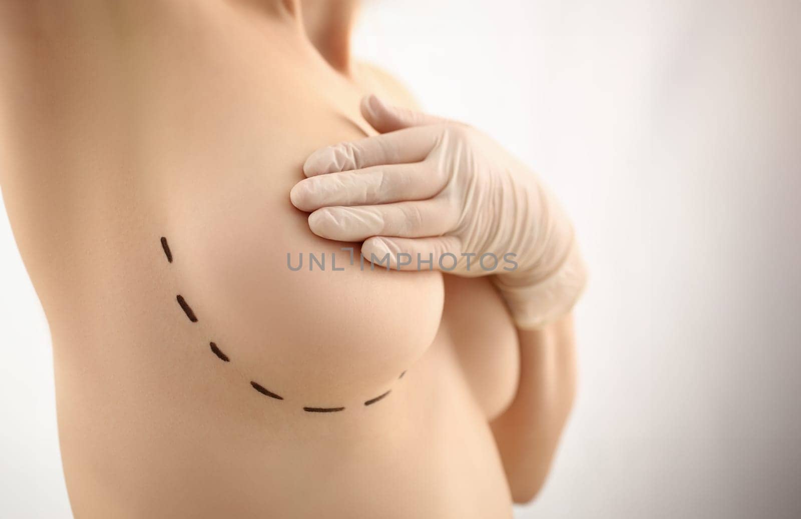 Female hand in gloves holding breast closeup on doctor mammology clinic reception. Mammary glands test biopsy implant silicone insert tumor human concept