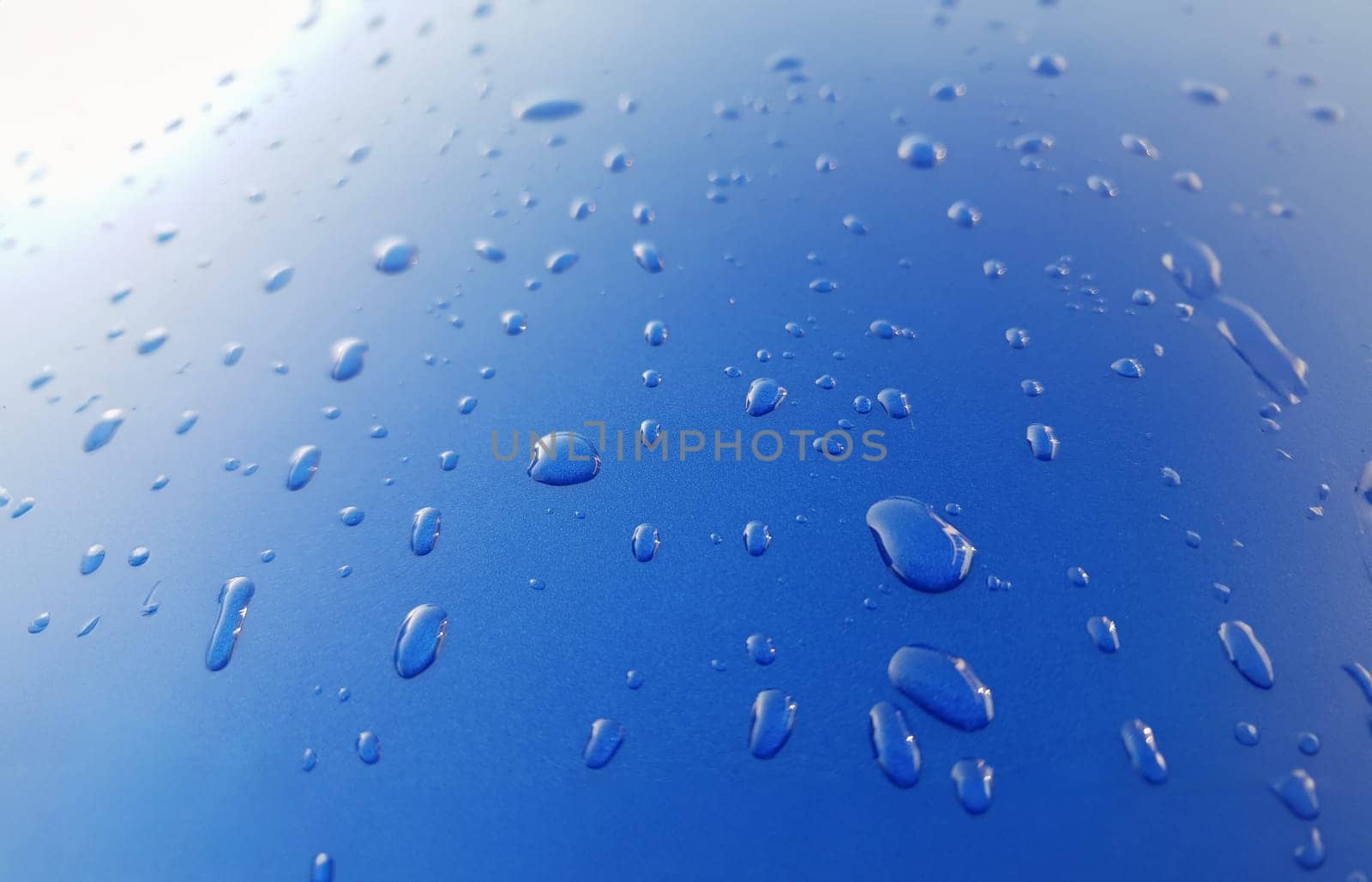 Drops of rainwater on blue metal background after nanoceramics polishing technology closeup