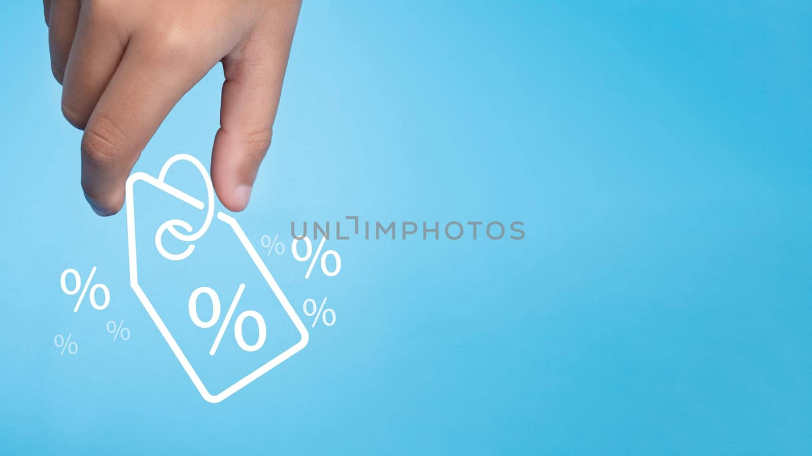 Human hand holds discount percentage sign icon on light blue background represents online shopping concept, special price products and promotions.