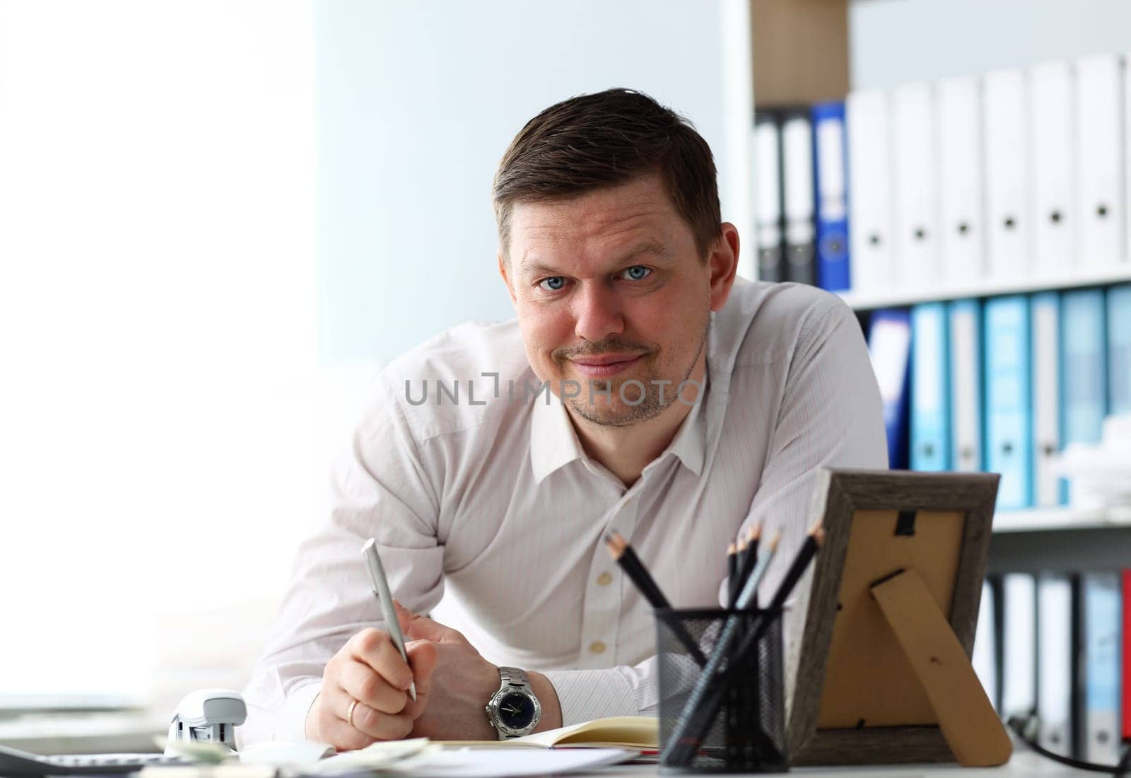 Handsome male clerk ar office working table looking in camera portrait