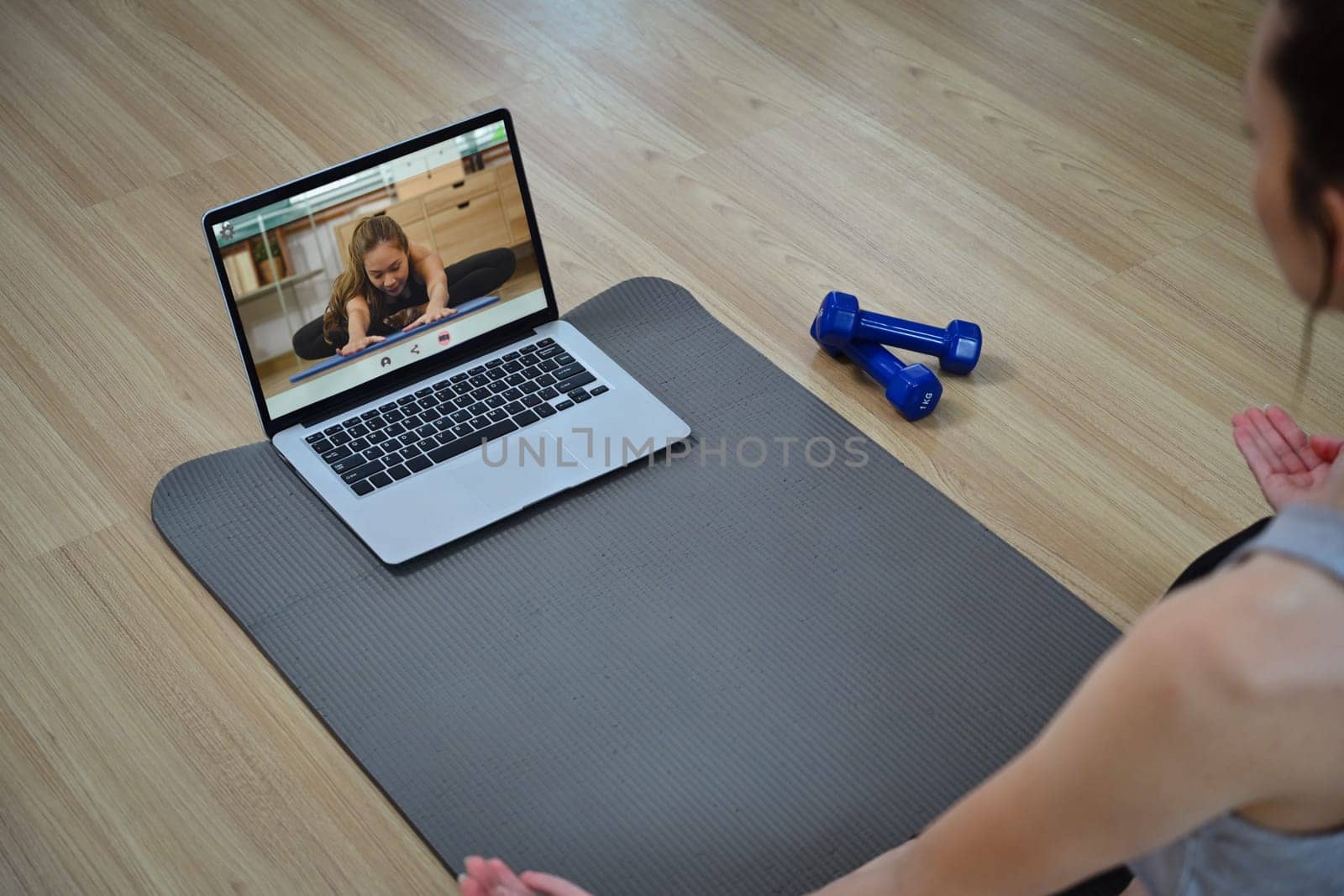 Sporty young woman doing online yoga watching training class online on laptop.