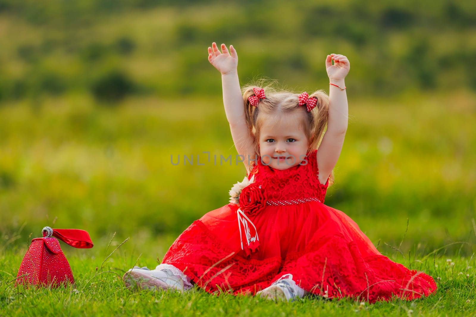 little girl in a red dress sitting on the lawn by zokov