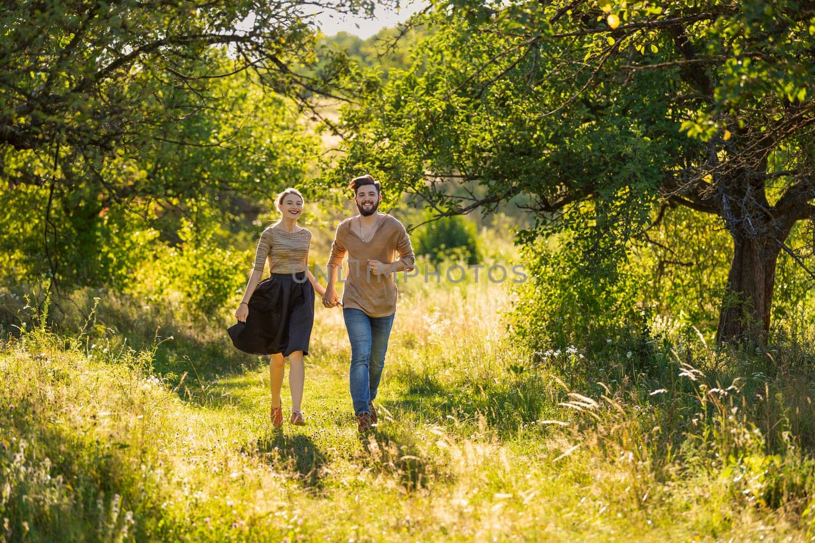 young couple walking in nature at sunset