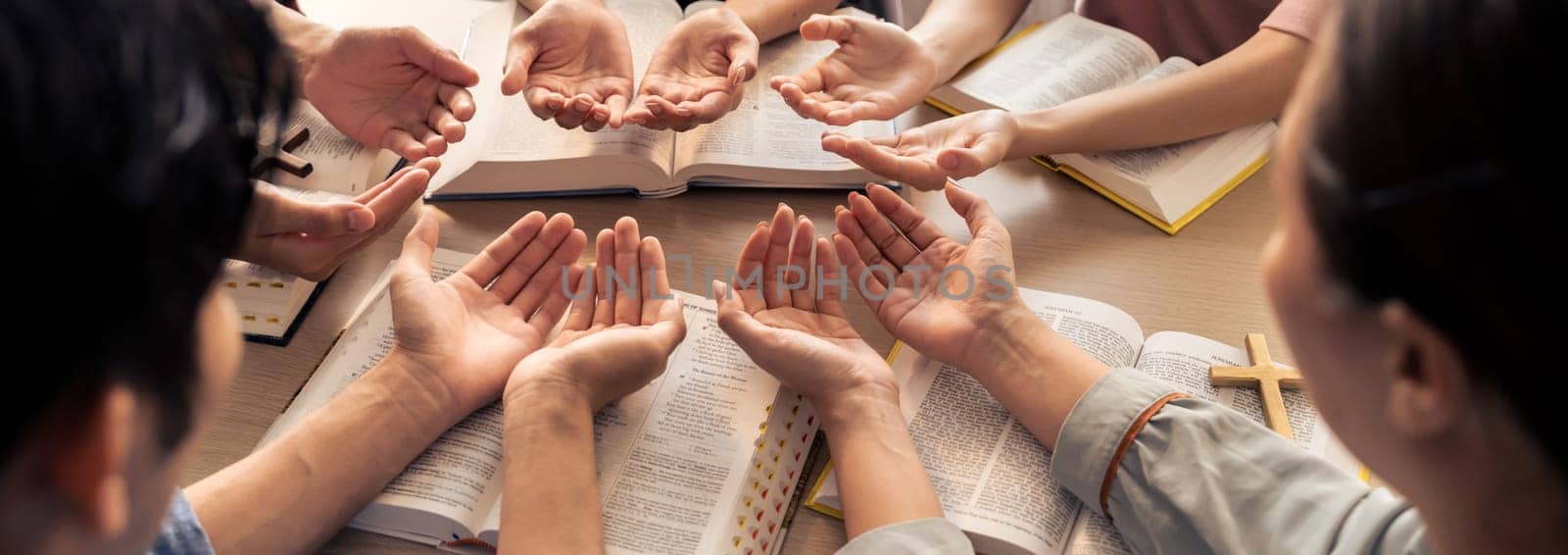 Cropped image of diversity people hand praying together at wooden church on bible book. Group of believer hold hand together faithfully. Concept of hope, religion, faith, god blessing. Burgeoning.