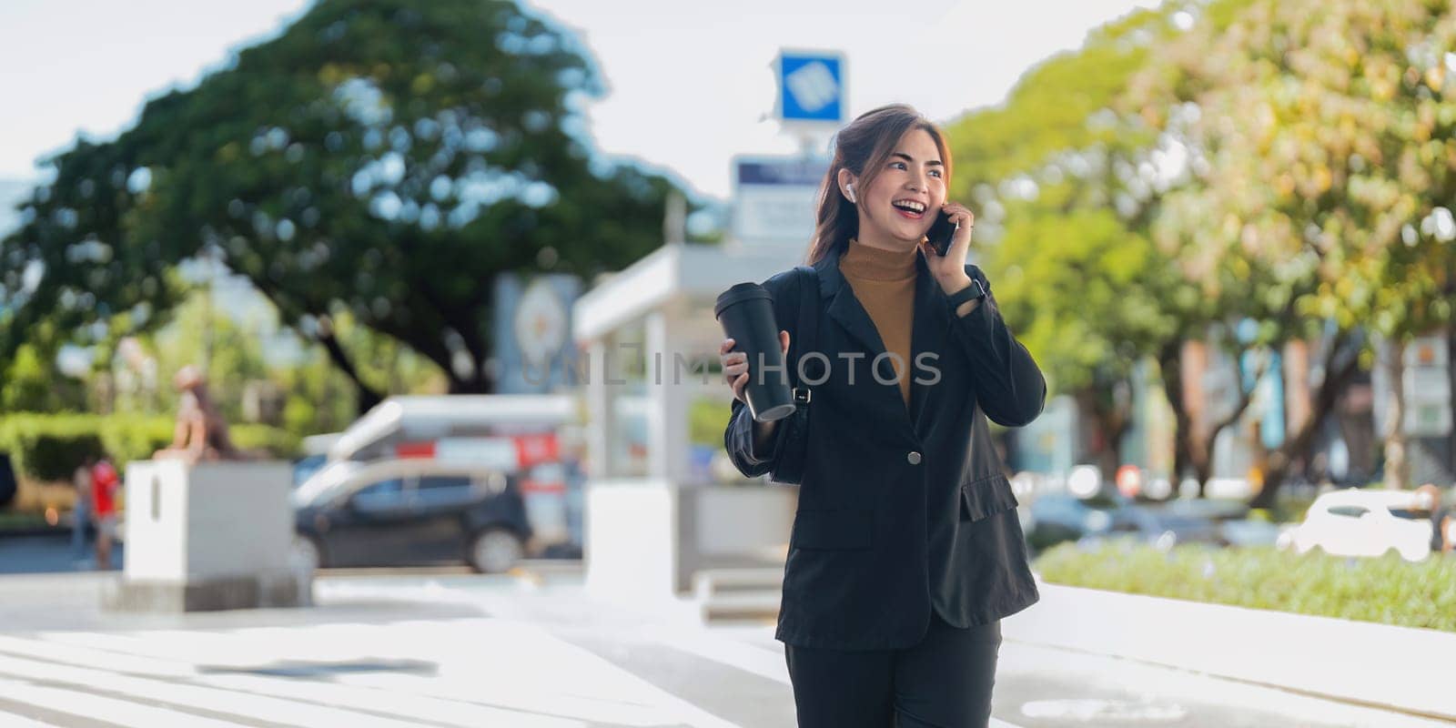 Asian professional businesswoman holding cellphone using smartphone standing or walking on big city urban street outside. Successful Asian business woman.