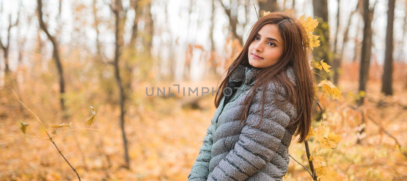 Close-up portrait of a young beautiful confident Indian Asian woman in fall outdoor. Happy and natural smiling female. Generation z and gen z youth