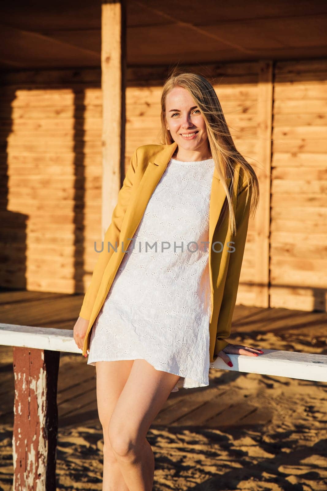 woman in a white dress sitting on a wooden building on the street walk