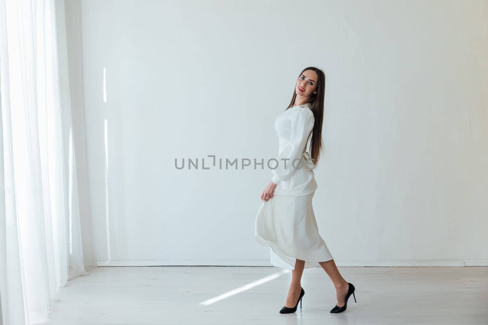 beautiful brunette woman posing on white fashion background in a bright room