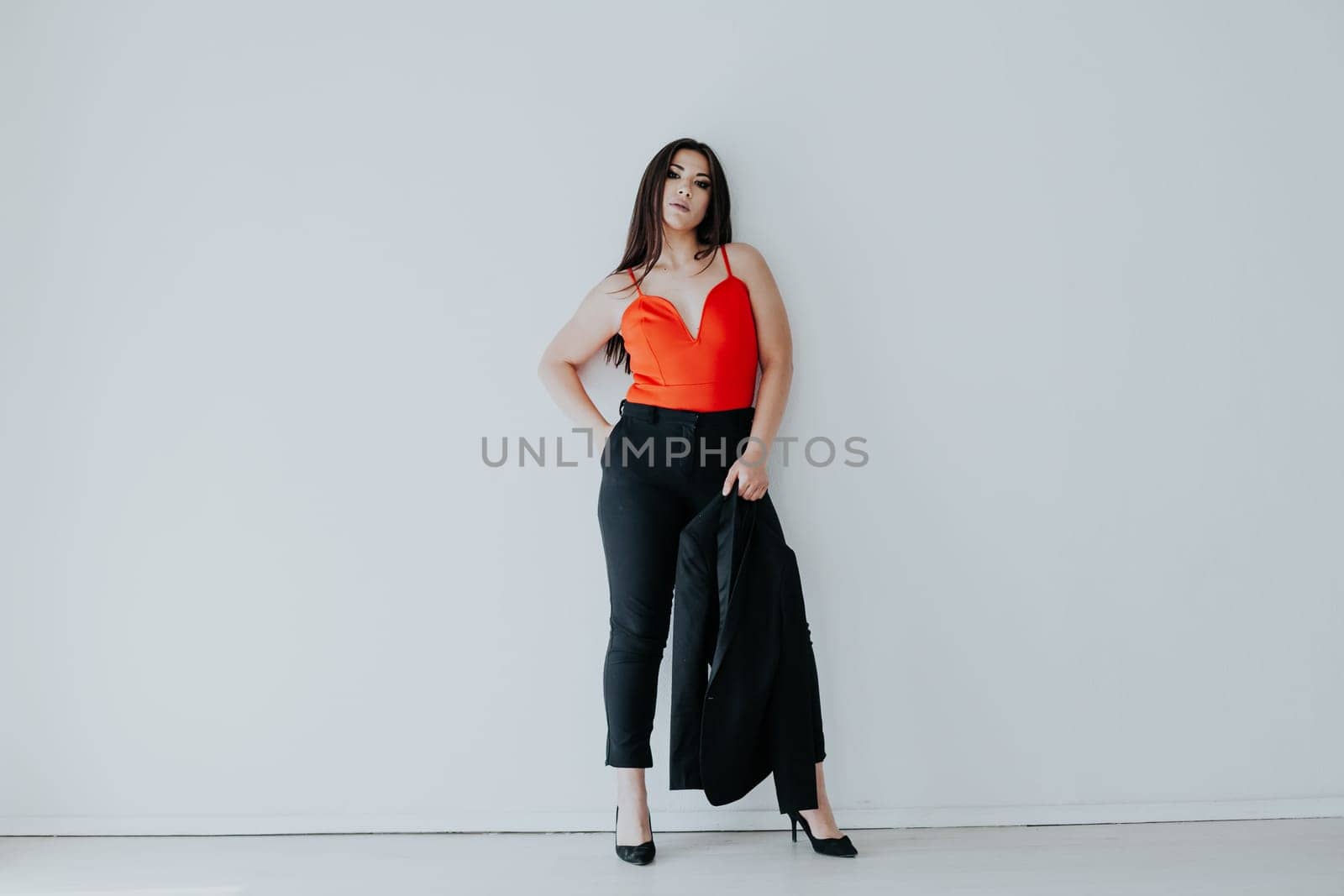 business woman stands on a white background with a jacket in her hand