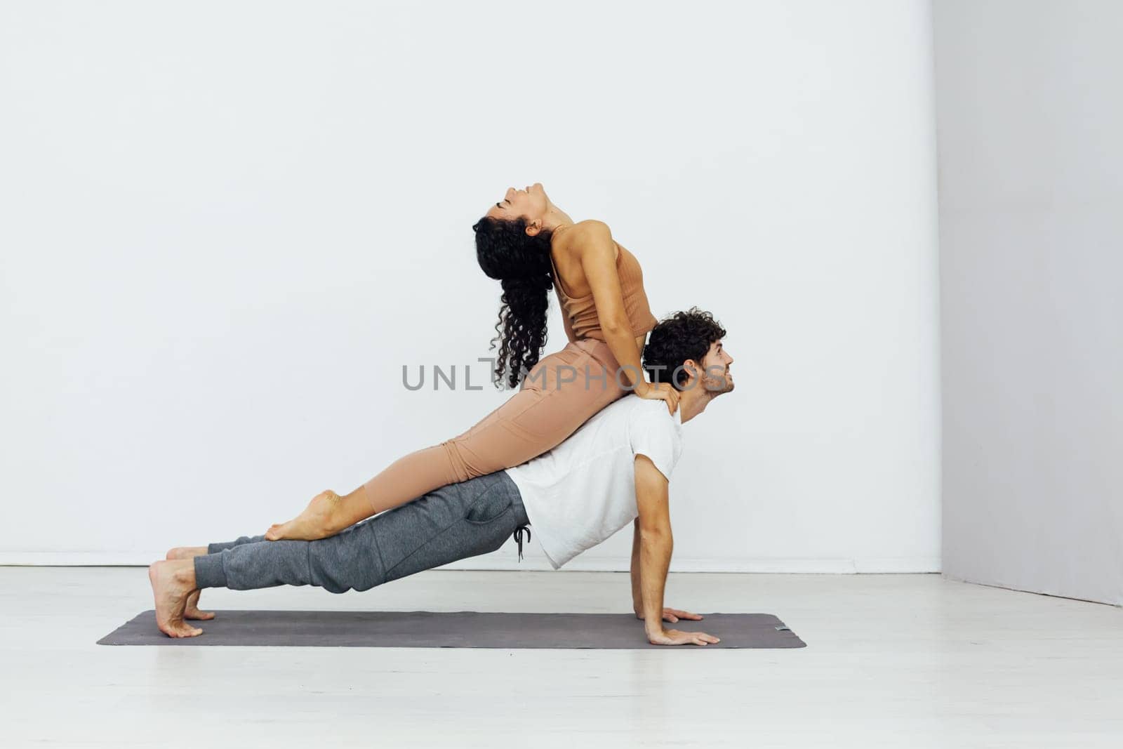 acrobatics yoga poses woman and man do gymnastics warm-up exercises asana flexible body by Simakov