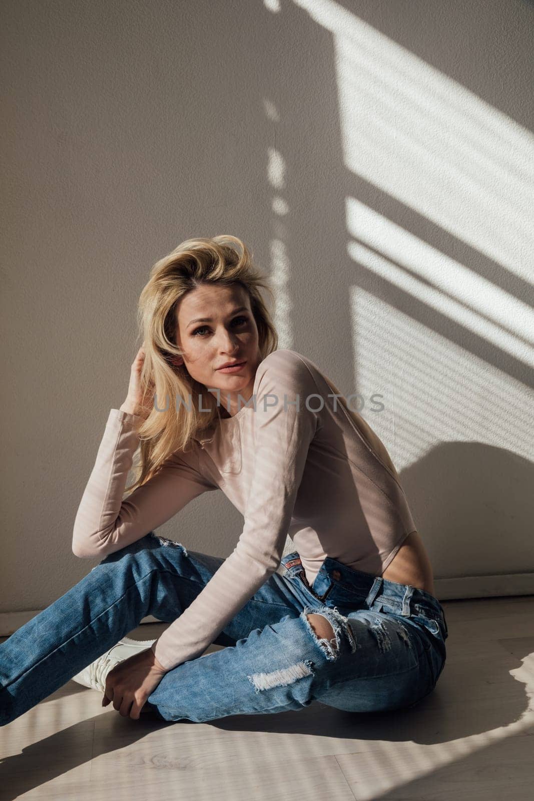 a blonde woman in jeans in sunset light in the room