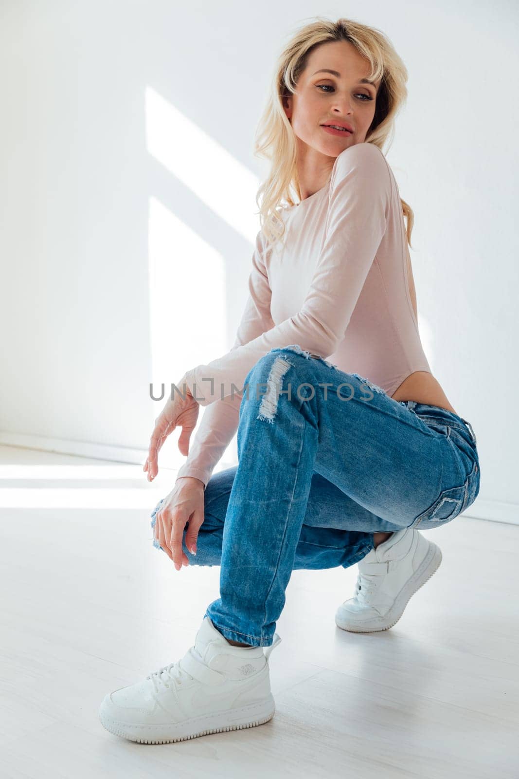 a blonde woman in jeans in a bright room