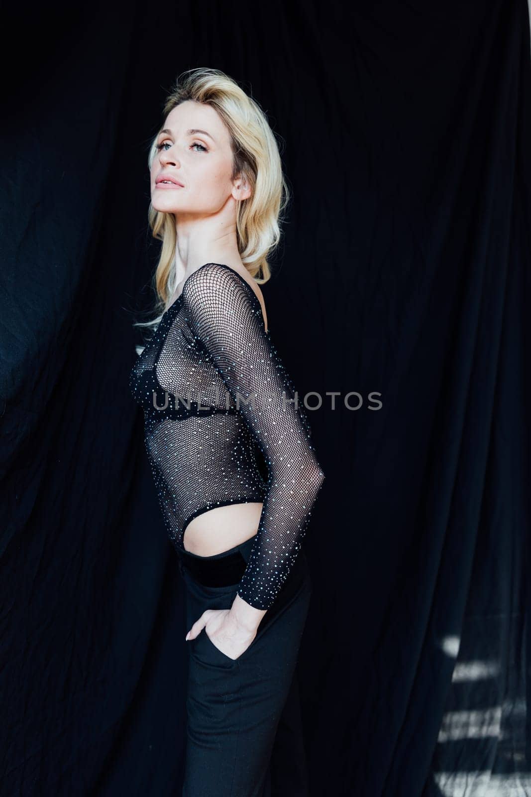 a beautiful blonde in black fashionable clothes on a black background
