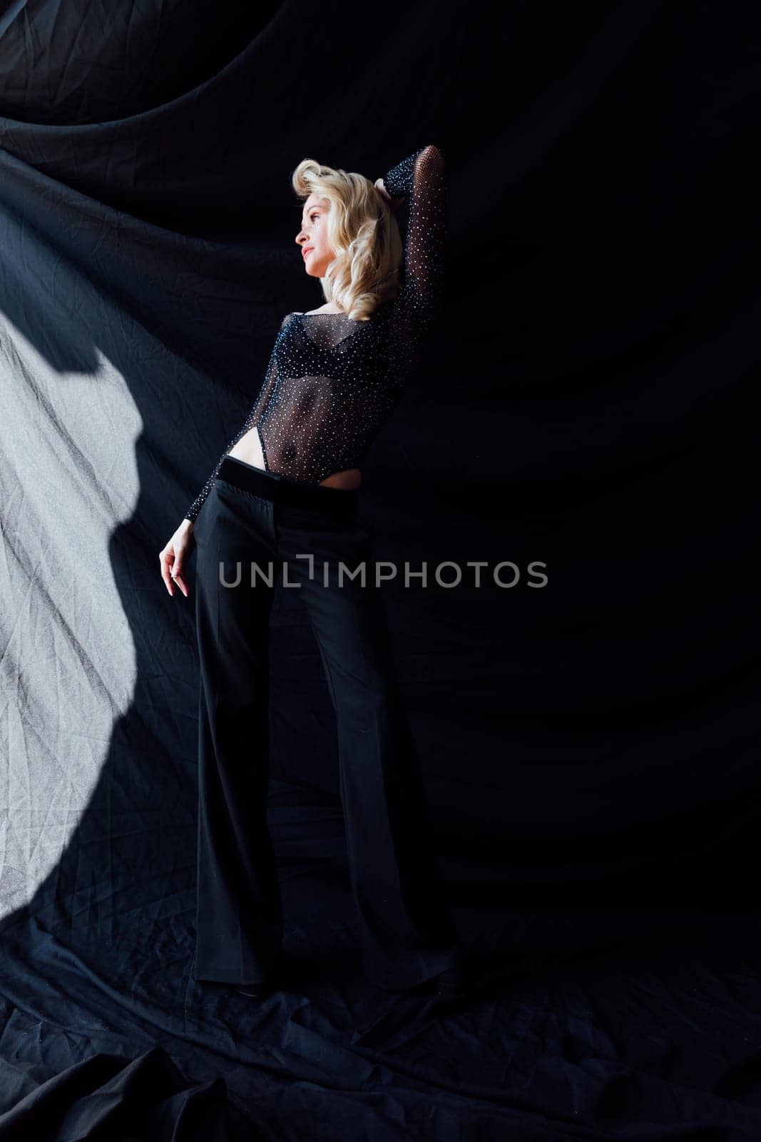 a beautiful blonde in black fashionable clothes on a black background