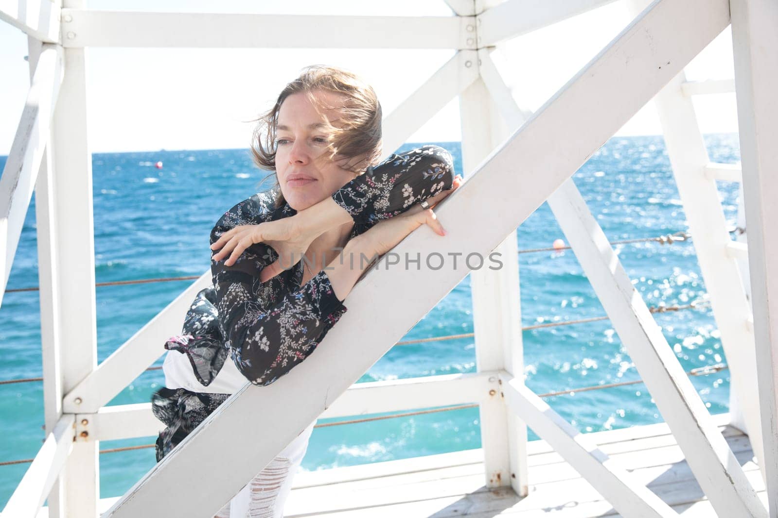 a woman by the sea near a wooden structure by Simakov